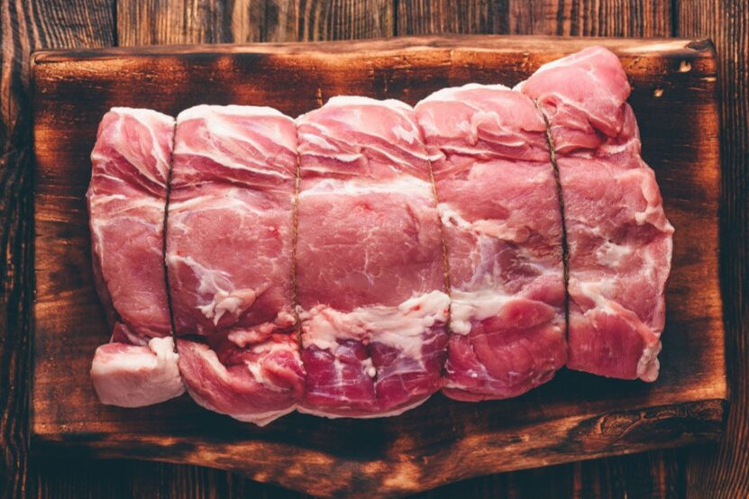 Raw pork roast on a wooden cutting board with a rustic background
