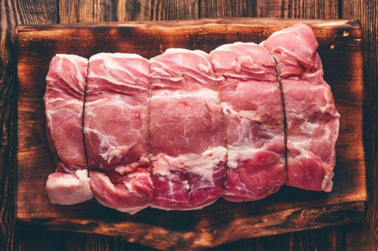 Raw pork roast on a wooden cutting board with a rustic background