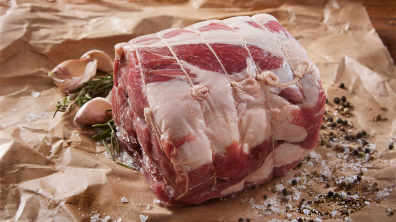 Raw meat roll with herbs and spices on brown paper