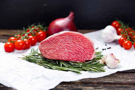 Raw steak with vegetables on a wooden surface